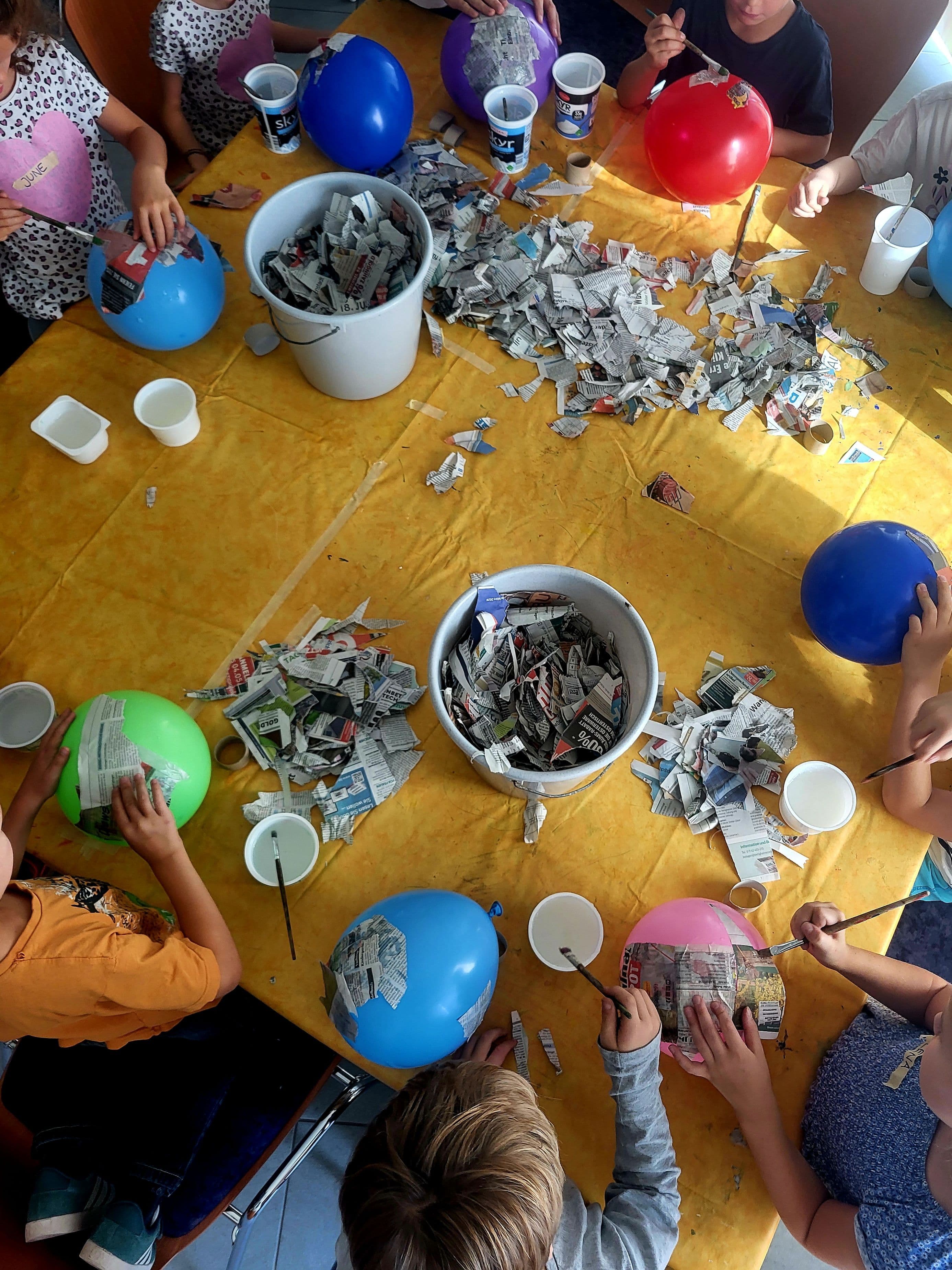 Kinder bekleben Luftballons mit Pappmaché