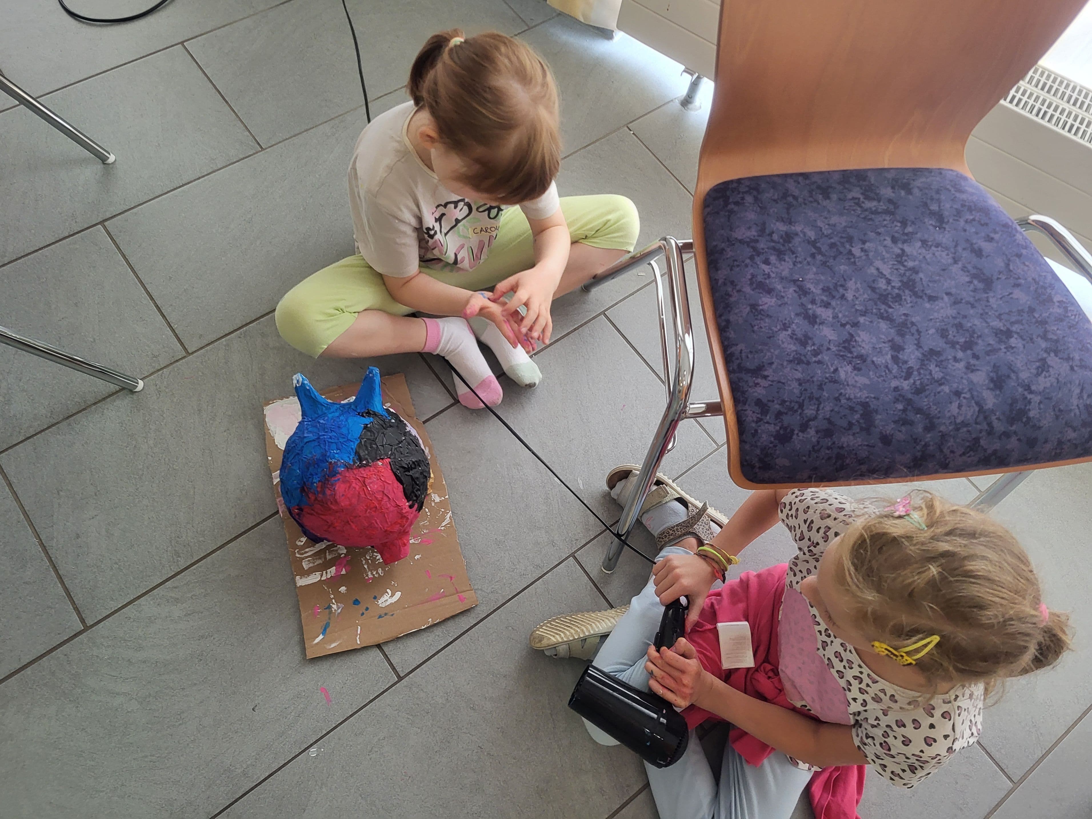 Kinder trocknen ihre bemalten Werke